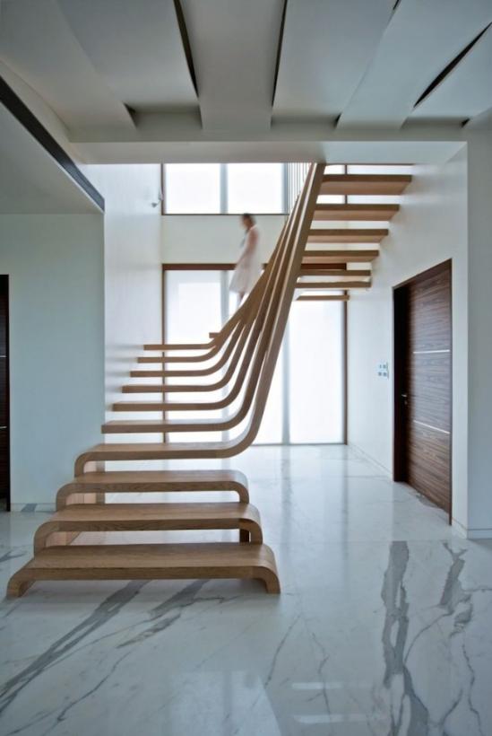 作为印度孟买SDM公寓项目的一部分 ，Arquitectura en Movimento Workshop在其间带来了这一设计极其精美的木制楼梯。它被建筑师设想为公寓内的功能性雕塑，因此有意似撇开了「扶手」这个安全因素，上下层楼梯板仿佛一体成型的流线型衔接在一块， 创建出流动和运动的感觉，并在巨大的落地窗下将整体营造成一个自然采光、通风的舒适空间。