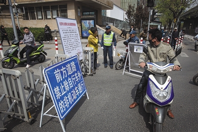 建外大街国贸桥下，有不知详情的市民向交管人员打听规定，有的在仔细查看规章指示牌。