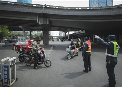 昨日，建外大街国贸桥下，两名交管人员告诉一名电动车驾驶者此路禁行，劝其改行其开奖直播路线。新京报记者 彭子洋 摄