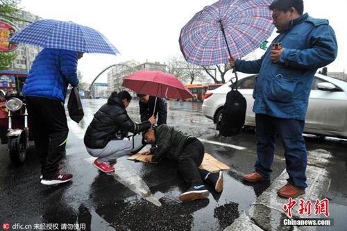 青岛老人路上摔倒 众人雨中撑伞救护