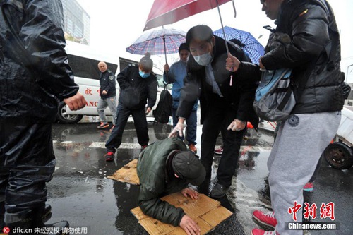 青岛老人路上摔倒 众人雨中撑伞救护