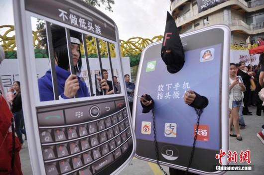 4月29日，重庆长江师范学院动漫协会的几名学生穿着动漫服装，举着手机模型，在涪陵红酒小镇内用行为艺术宣传不做低头族，倡导文明出行。陈超 摄