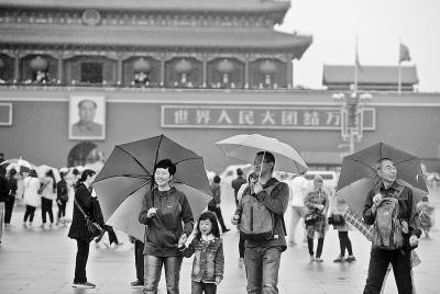 昨天，游客在雨中游览天安门。记者 方非摄