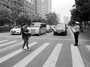 协警手持礼让牌站在斑马线前偬嵝牙赐车辆 记者 吴依滢摄