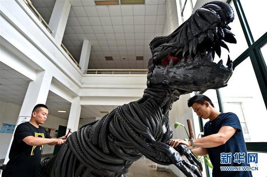 5月28日，河南洛阳师范学院大学生在对“轮胎恐龙”进行修整。