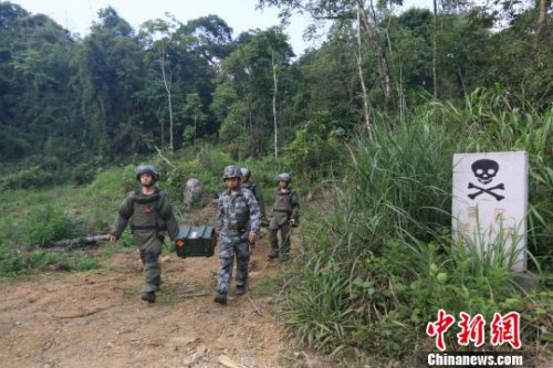 官兵排雷结束，抬着装备和搜排出的爆炸物走出雷场。 郭赣荣 摄