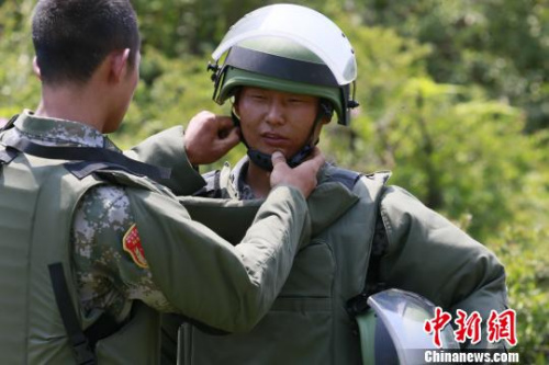 出征之前，扫雷官兵互相整理检查防护装具。 严浩 摄