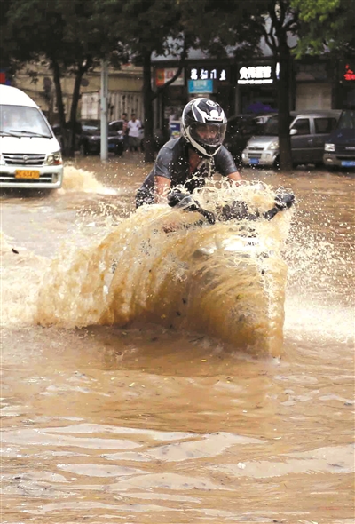 普照红绿灯路口积水严重，市民骑车经过。