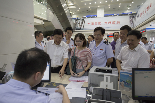 图为 税务总局党组成员、副局长汪康在广州市海珠区国地税办税服务厅了解税务机器人运行情况