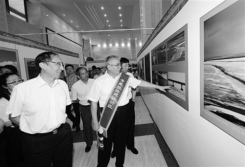 7月1日，由中国西藏文化与保护发展协会与中国铁建联合主办的青藏铁路通车10周年图片展在北京开展。图为青藏铁路建设者在参观图片展。经济日报记者 齐 慧摄