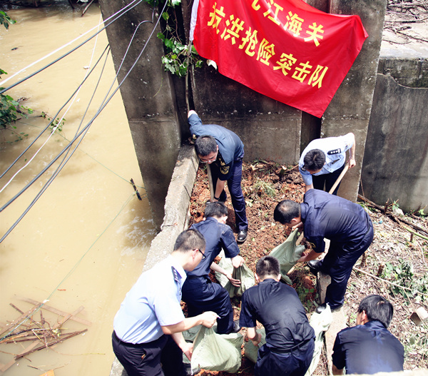 图为：抗洪抢险队员合力清除闸口杂物