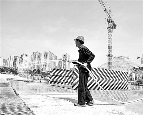 右图 重庆沙坪坝区大学城一建筑工地，工人正在高温天气下进行洒水作业。赵杰昌摄