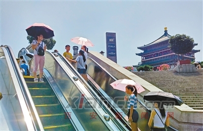高温下，许多市民打遮阳伞出行。 首席记者 张宇明 实习生 张敏 摄