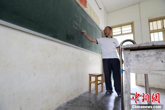 在广西柳州市融安县东起乡的偏僻山坳里，有一所“微小学”——东起乡长丰村小学，2016年秋季学期，这里只有12名学生和一名叫李朝文的老师。李老师年过五十且腿部有残疾，执教38年来，他默默坚守在三尺讲台上，守护着大山里的孩子，被当地人誉为“最美乡村教师”。1986年，李朝文老师在学生家访途中腿部摔伤，落下残疾。在腿部受伤后，李朝文拄着拐杖一直坚守在三尺讲台上，至今已经第30个年头。近年来，随着村民外出人数增多，这里上学的孩子也越来越少，老师们也陆续离开，李朝文却一直坚守在这里，独自一人担负起给孩子们教授语文、数学、音乐等6门课程的重任，风雨无阻。他教过的学生，有超过100名学生考上县里或市里的重点高中，有的还考上清华等名牌大学，走出了大山。谭凯兴 摄