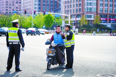 昨天早晨，在长安街东单路口，交警对一辆正要拐弯驶上长安街的电动自行车驾驶员进行劝导。 本报记者 邓伟摄